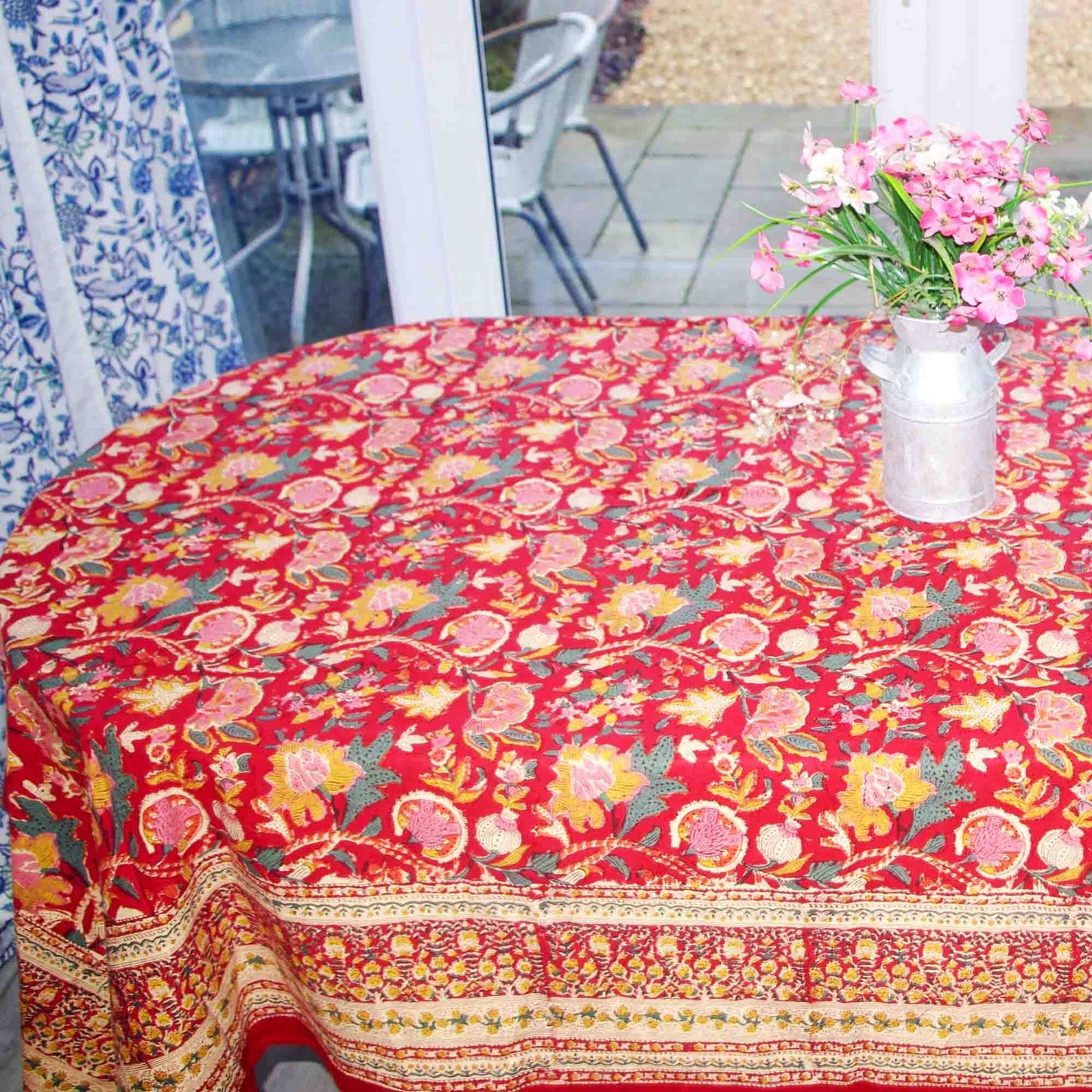 Colorful floral-patterned tablecloth on a table with a vase of flowers.