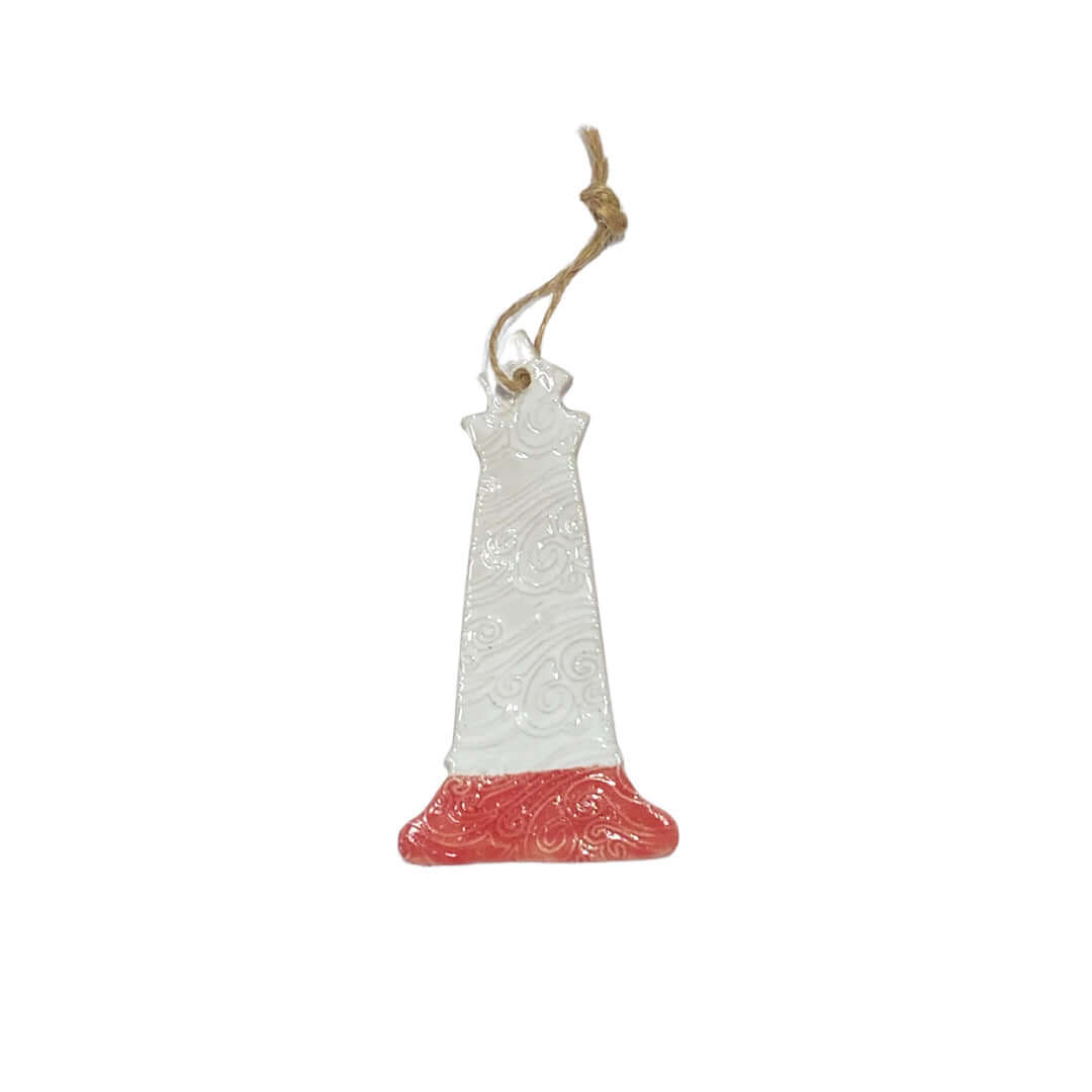 A ceramic lighthouse decoration with a white body, red base, and grey accents, hanging from a jute string.