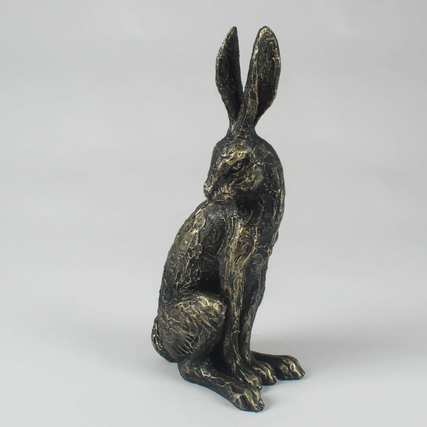 A resin standing hare statute with a distressed gold and black finish, looking back over its shoulder.