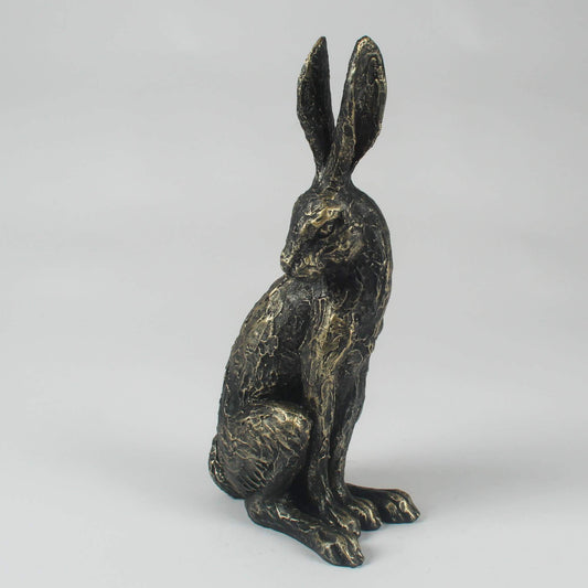 A resin standing hare statute with a distressed gold and black finish, looking back over its shoulder.
