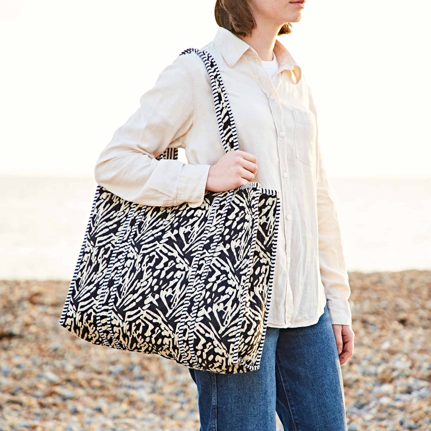 Person holding a patterned bag on a beach