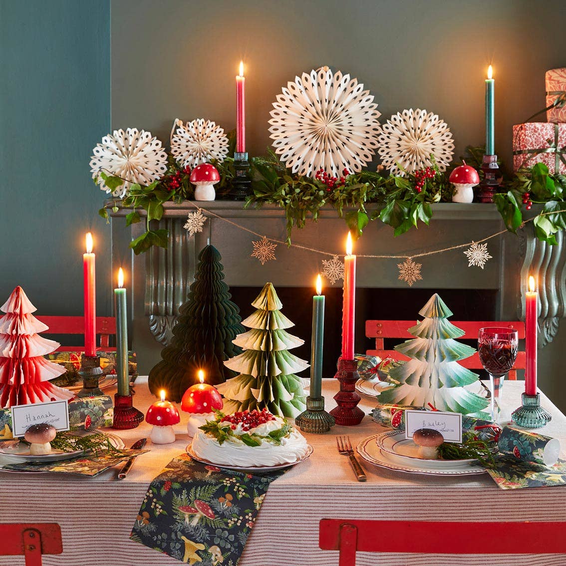 Decorative Christmas table setting with candles, trees, and garlands.