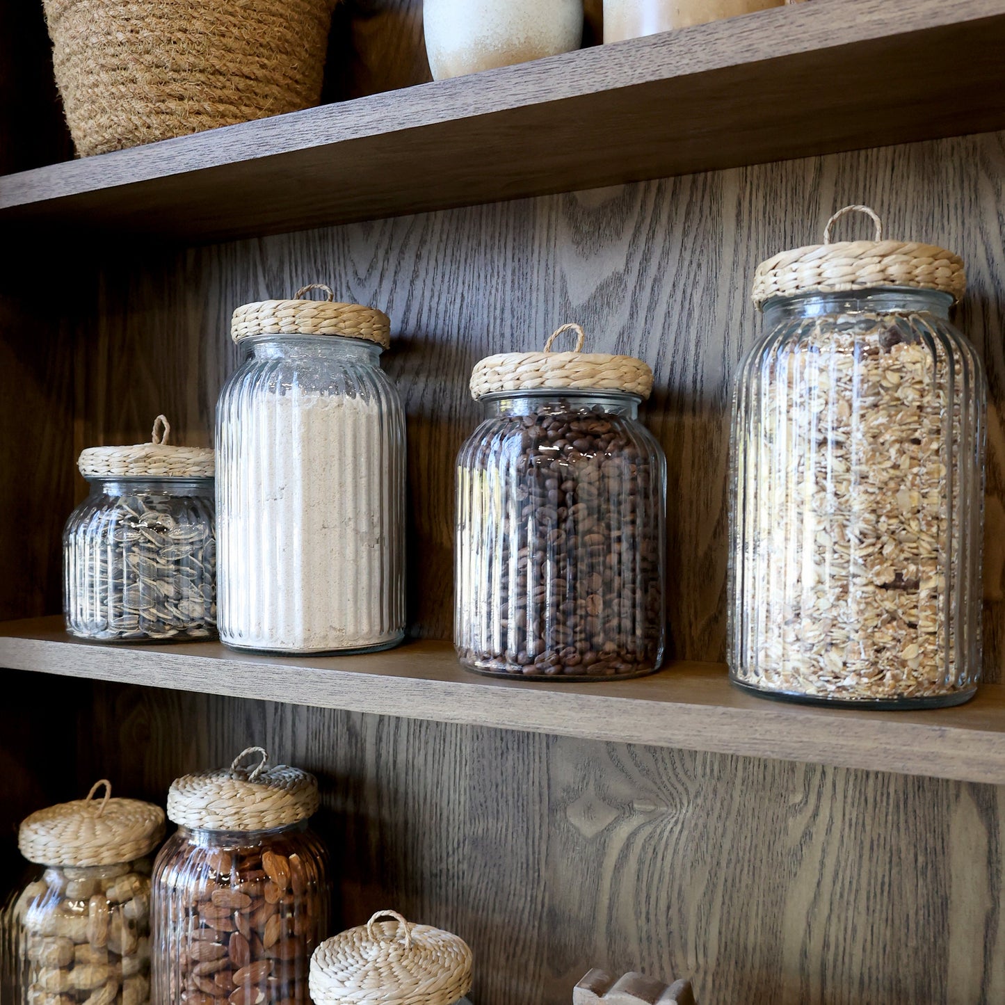 Ribbed glass storage jar with wicker lid on a dresser