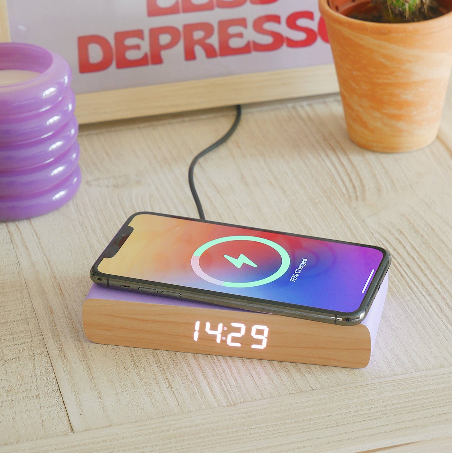 Smartphone on a wooden dock with digital display, charging on a light wood surface.