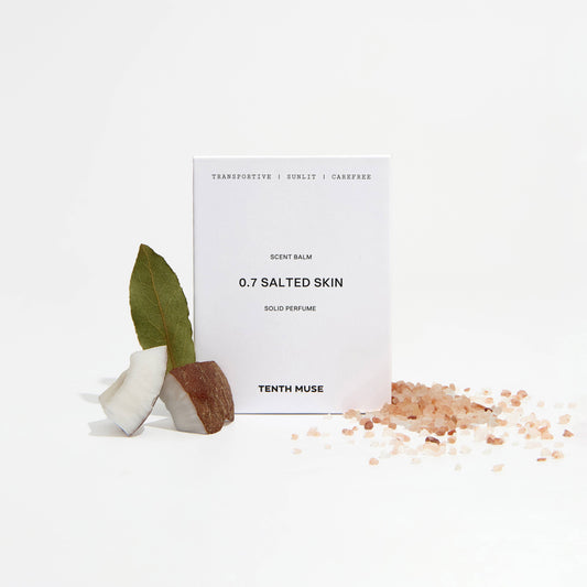 Perfume balm labeled '0.7 Salted Skin' by Tenth Muse with a small plant and salt crystals on a white background.