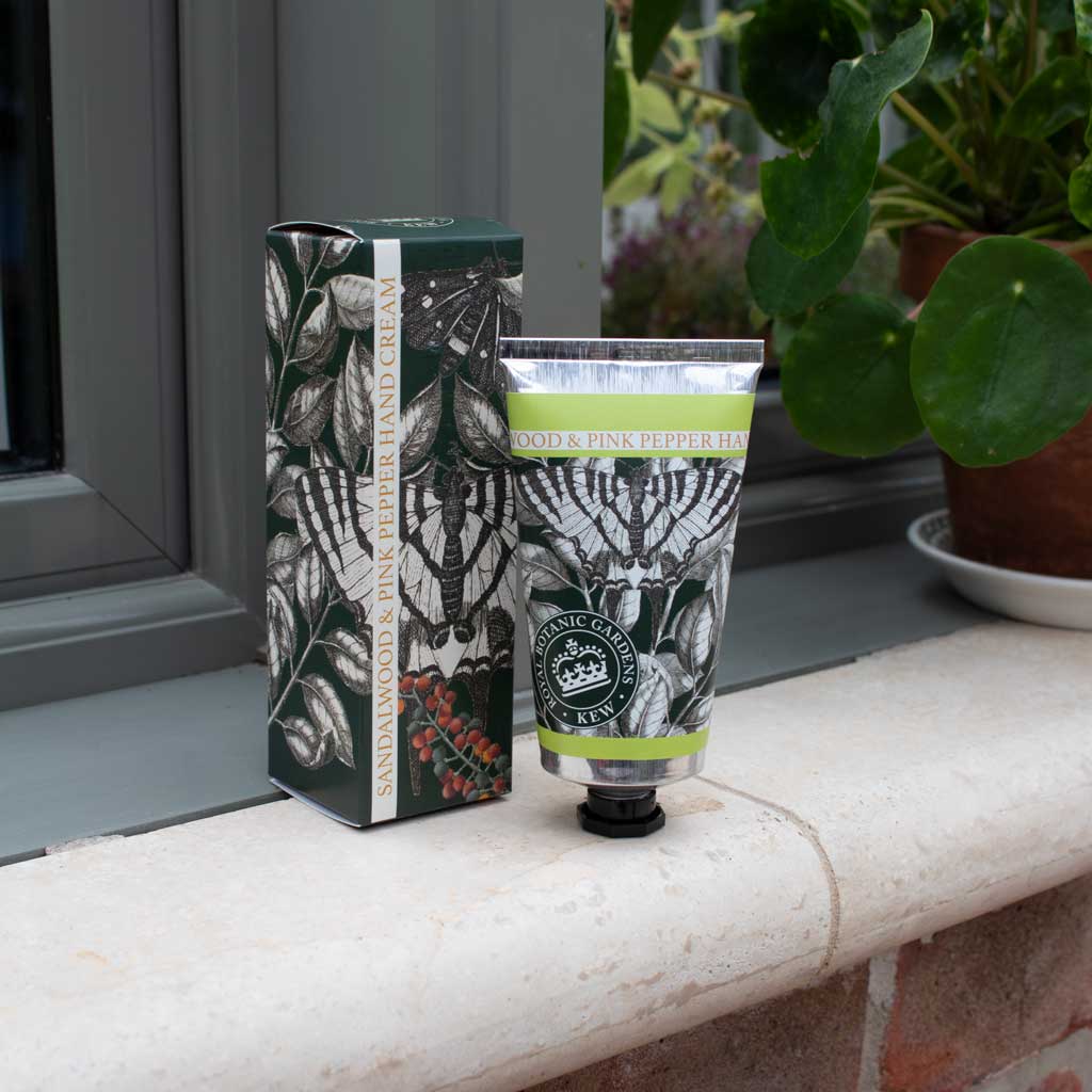 Hand cream with packaging on a windowsill with plants in the background