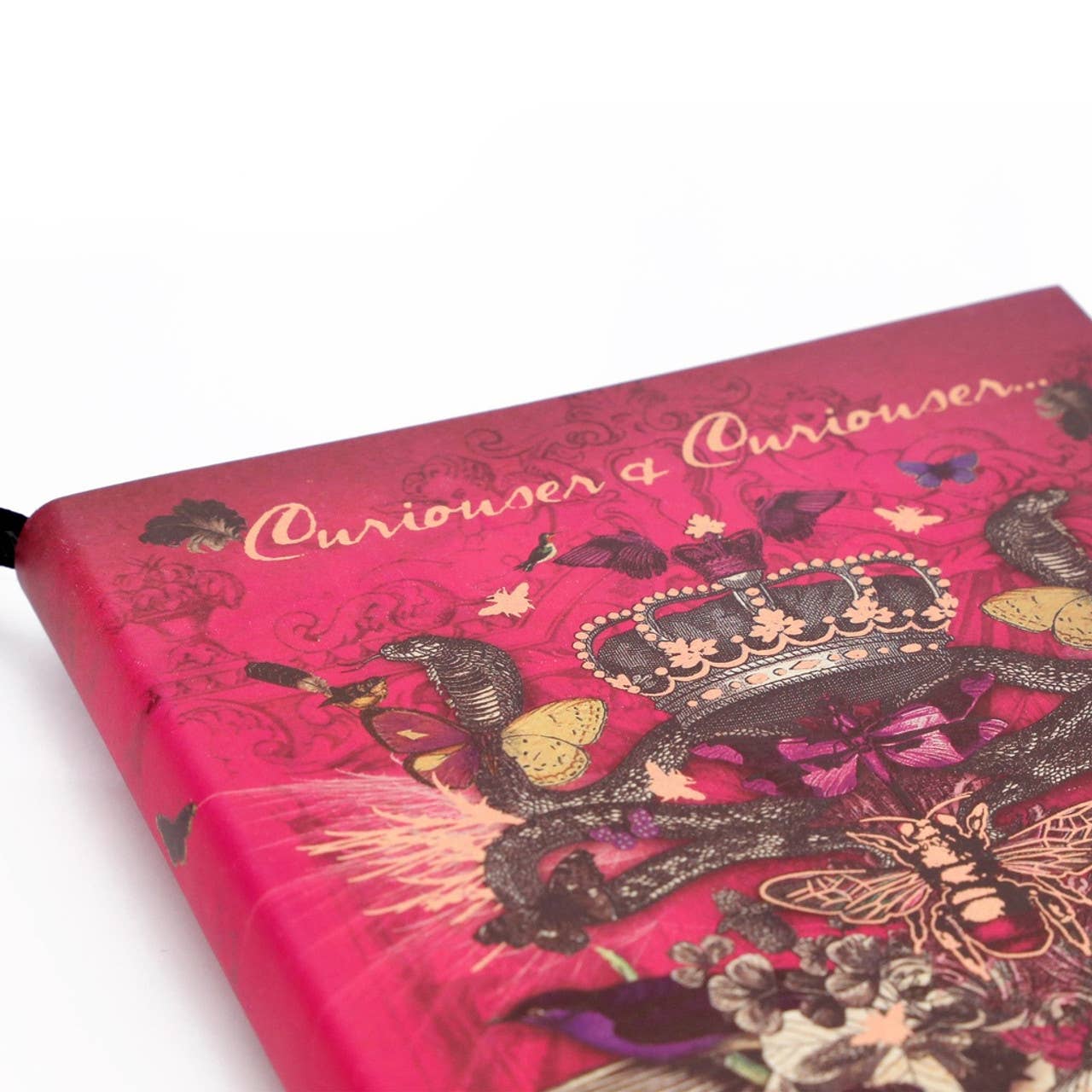Pink notebook with intricate designs and 'Curiouser & Curiouser' text on a white background