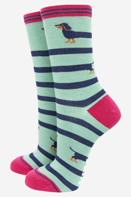 Pair of socks with green, navy, and pink stripes and dachshund designs on a white background