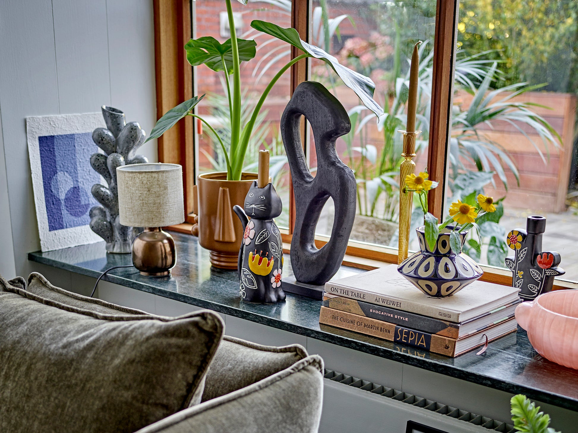 Decorative items on a windowsill with books, sculptures, and plants.