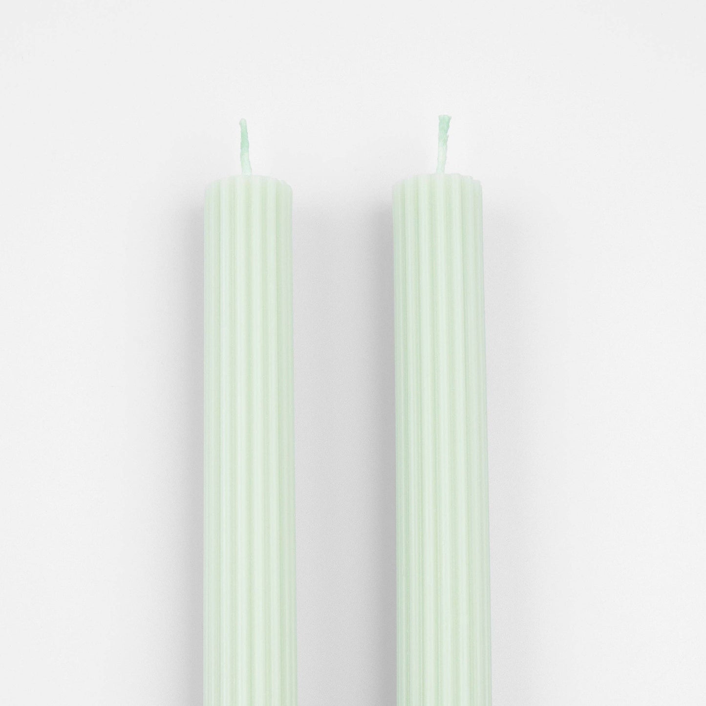 Two light green candles on a white background