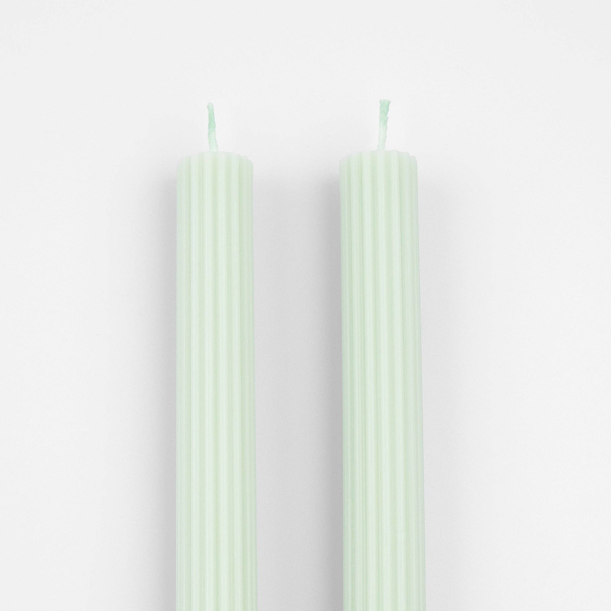 Two light green candles on a white background
