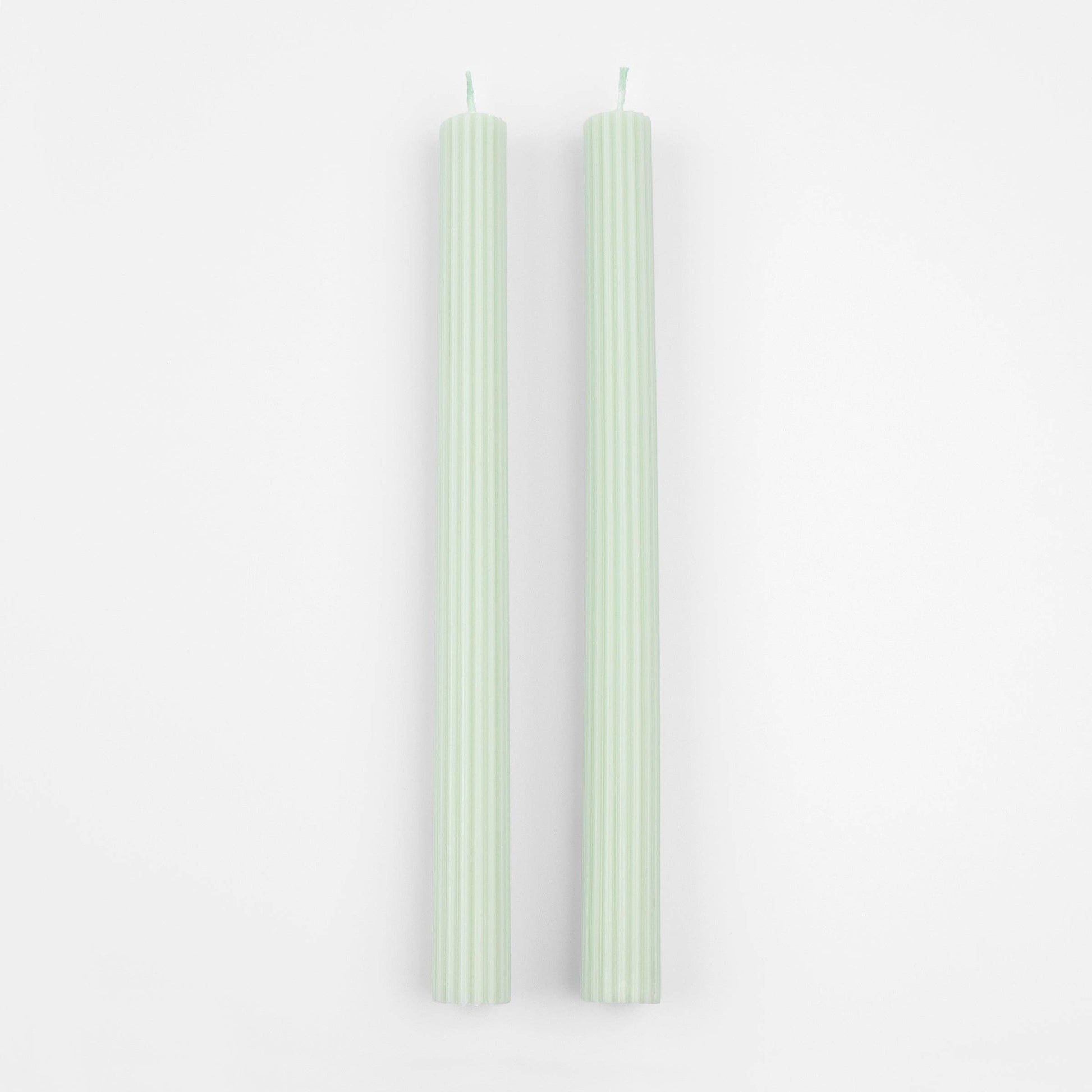 Two green candles on a white background