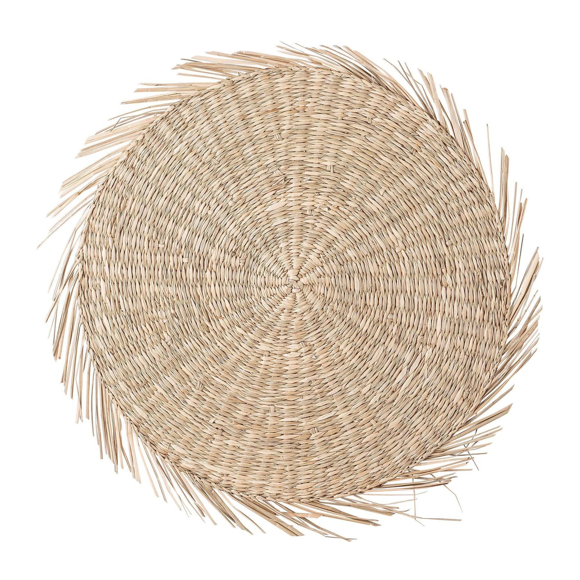 A round woven natural fiber placemat with a frayed, palm-leaf-like border, shown from a top-down view on a solid white background.