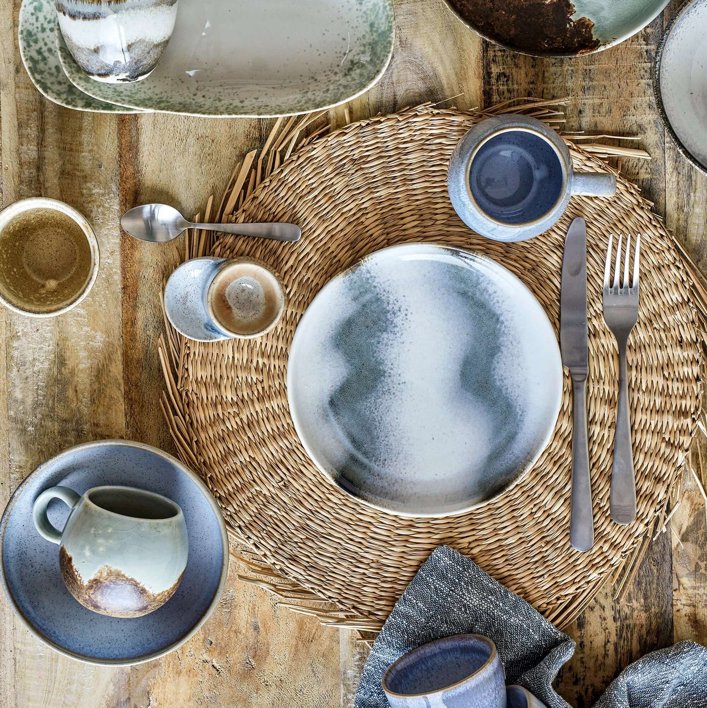 Table setting with ceramic plates, cups, and cutlery on a wooden surface