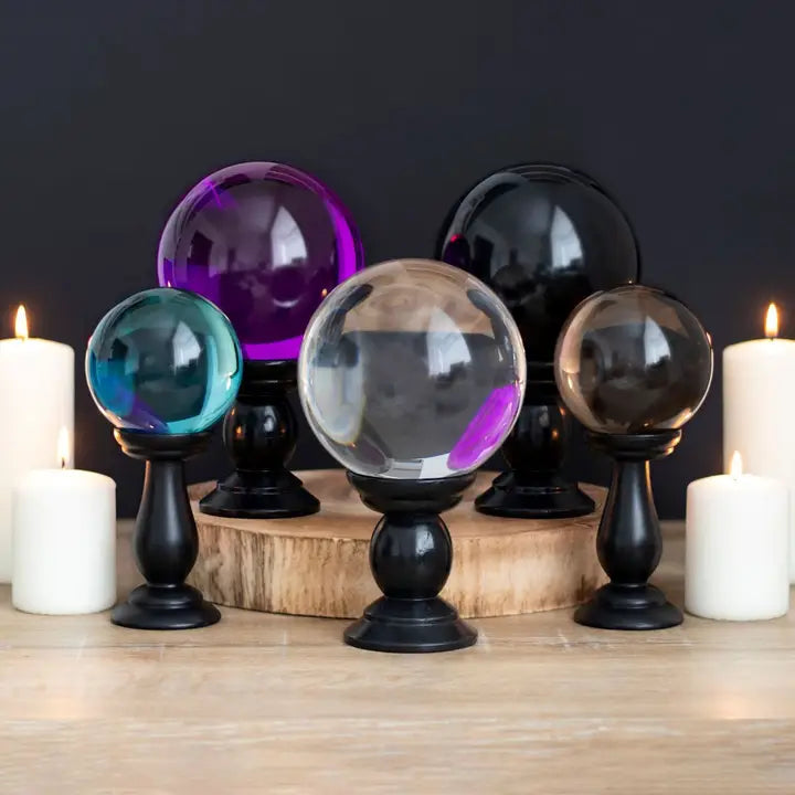 Set of colorful crystal balls on stands with candles in the background