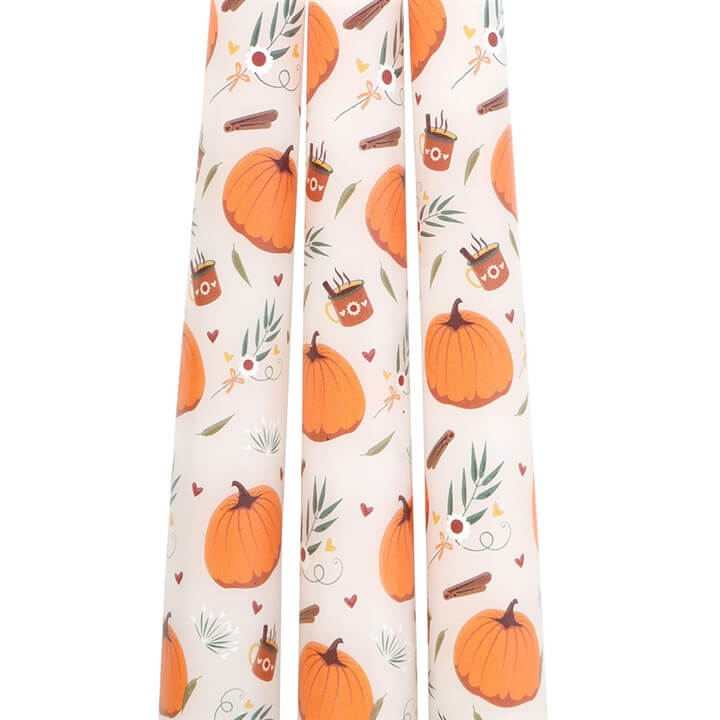 Set of three candles with pumpkin and owl design on a white background