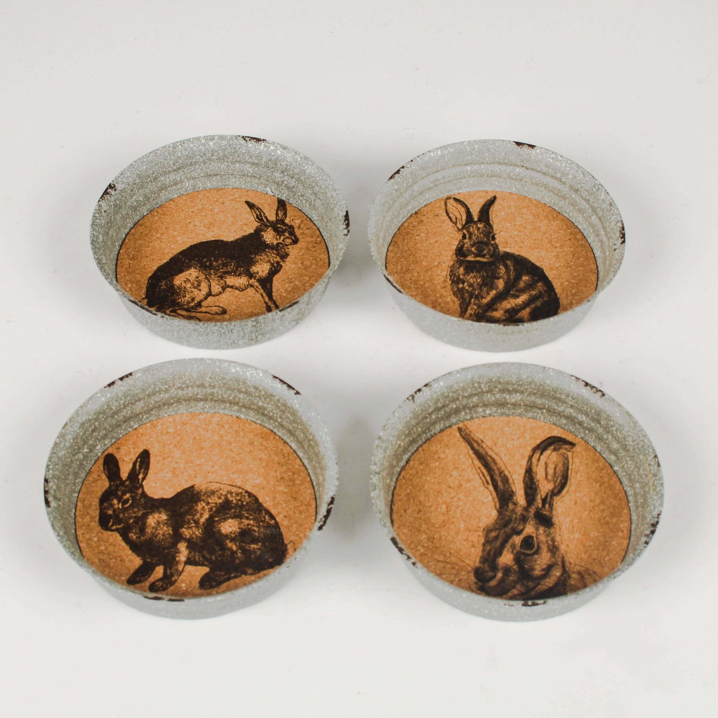 A set of four round coasters with cork backing, each featuring a different black and white illustration of a hare.