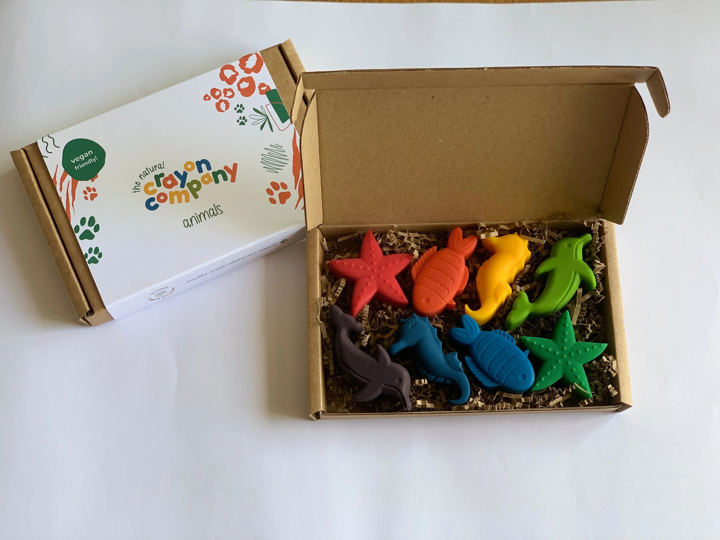 Box of colorful seaside themed-shaped crayons toys with a branded card on a white background