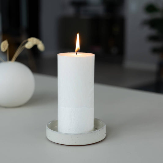 White candle in a concrete holder on a blurred background