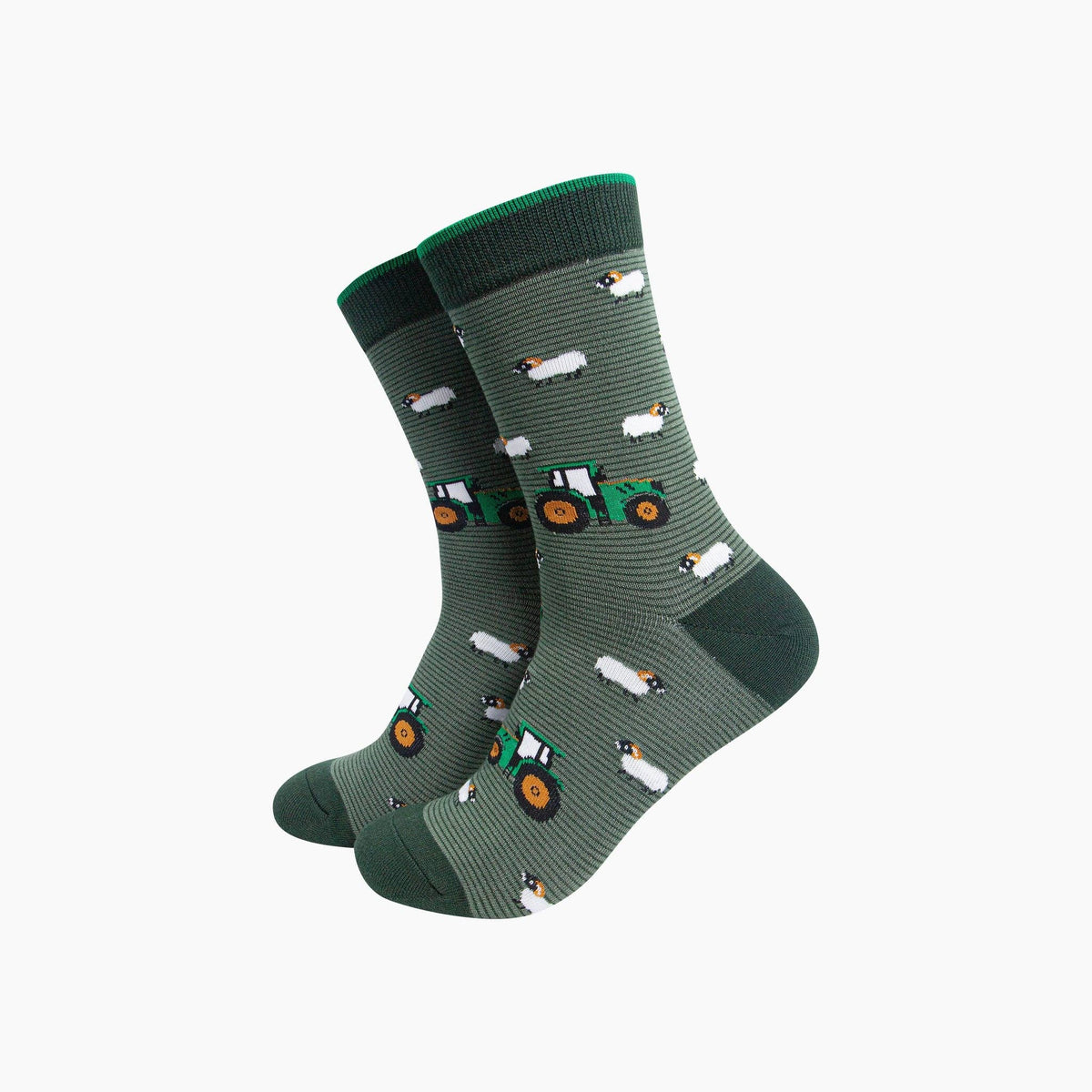 A pair of crew socks in dark green with a pattern of small white sheep and green tractors, shown on a plain light gray background.