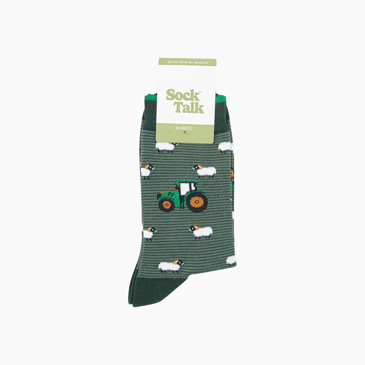 A pair of Sock Talk bamboo socks featuring a green tractor and white sheep pattern on a dark green striped background, shown with their retail packaging against a plain white background.