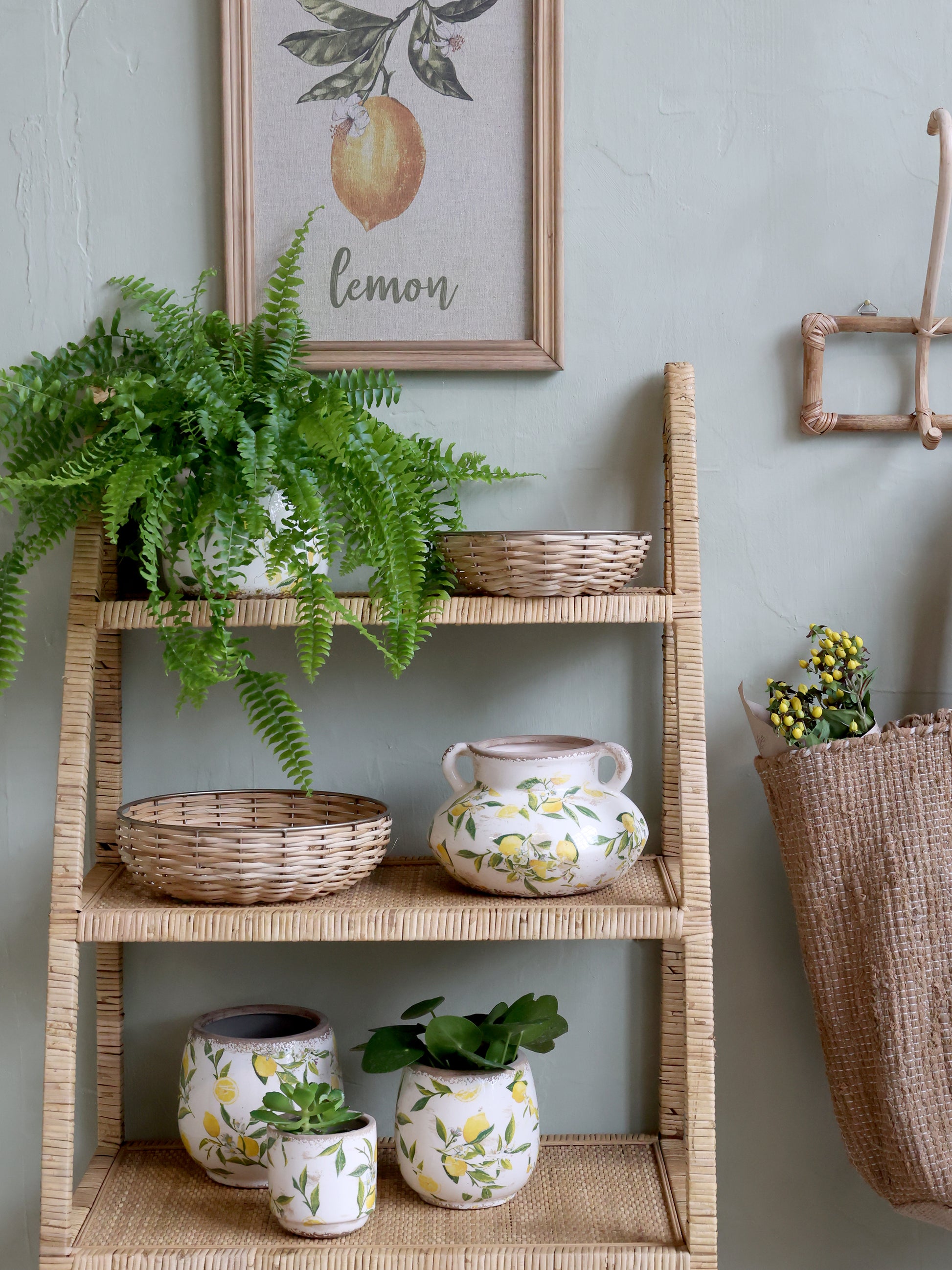 Wicker shelf with plants and decorative items against a light gray wall.