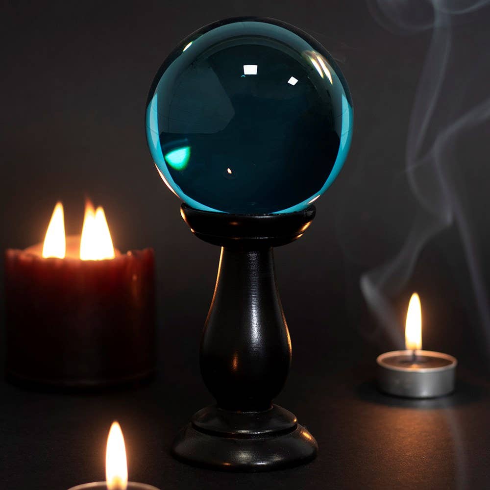 Blue crystal ball on a stand with candles in the background