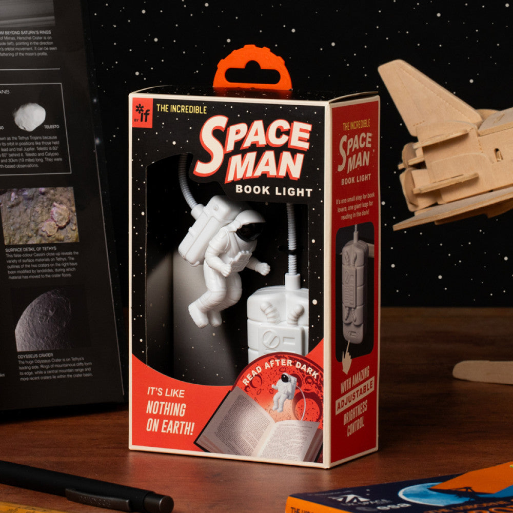Space-themed book light packaging with astronaut design on a wooden surface.
