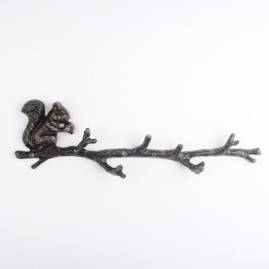 Decorative metal squirrel on a branch row of hooks with a white background
