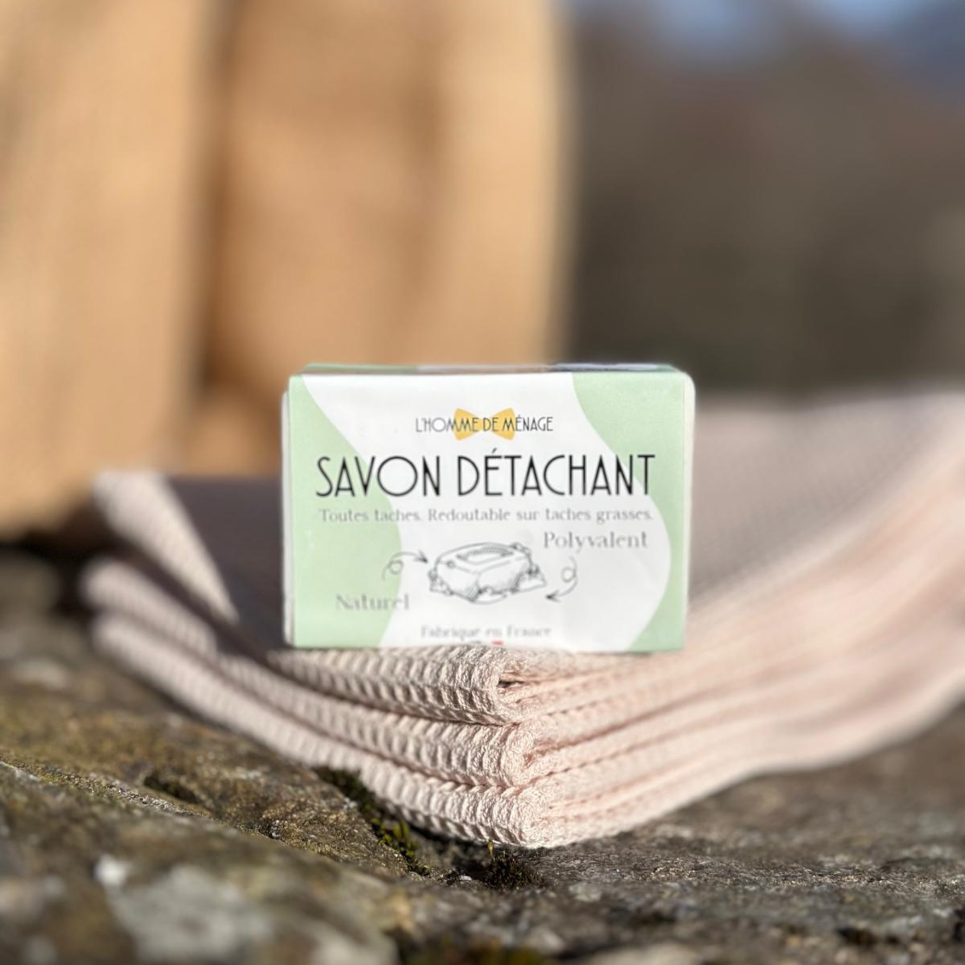 Bar of soap with packaging labeled 'Savon Detachant' on a stone surface.