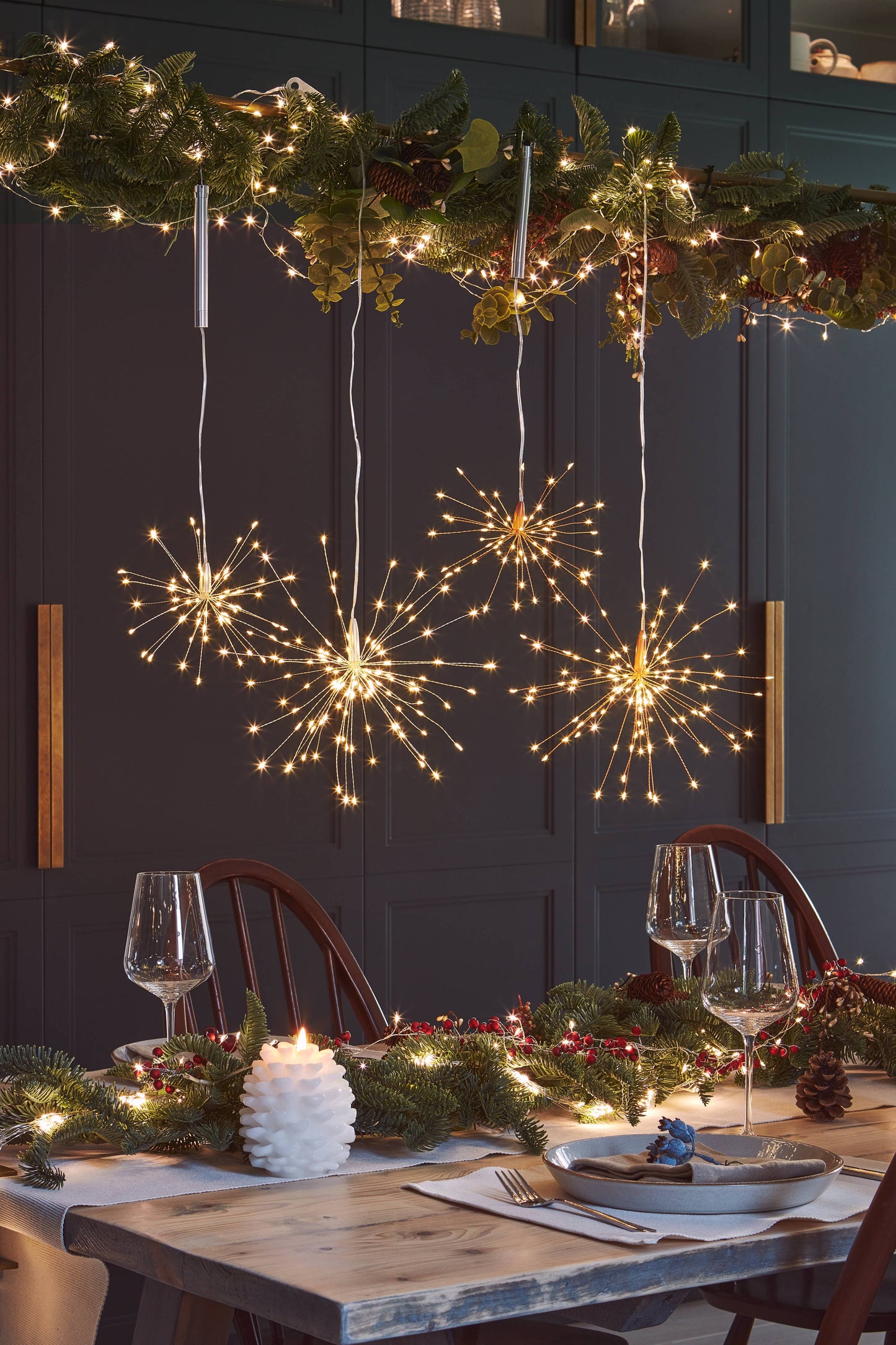 Decorative table setting with string lights shaped like fireworks and a garland above.