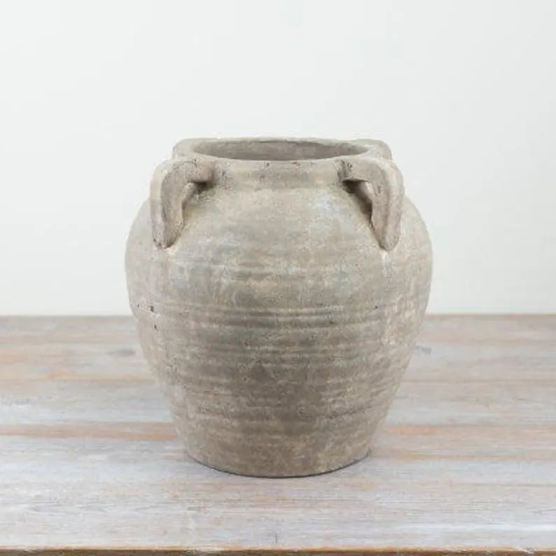 Terracotta pot with handles on a wooden surface