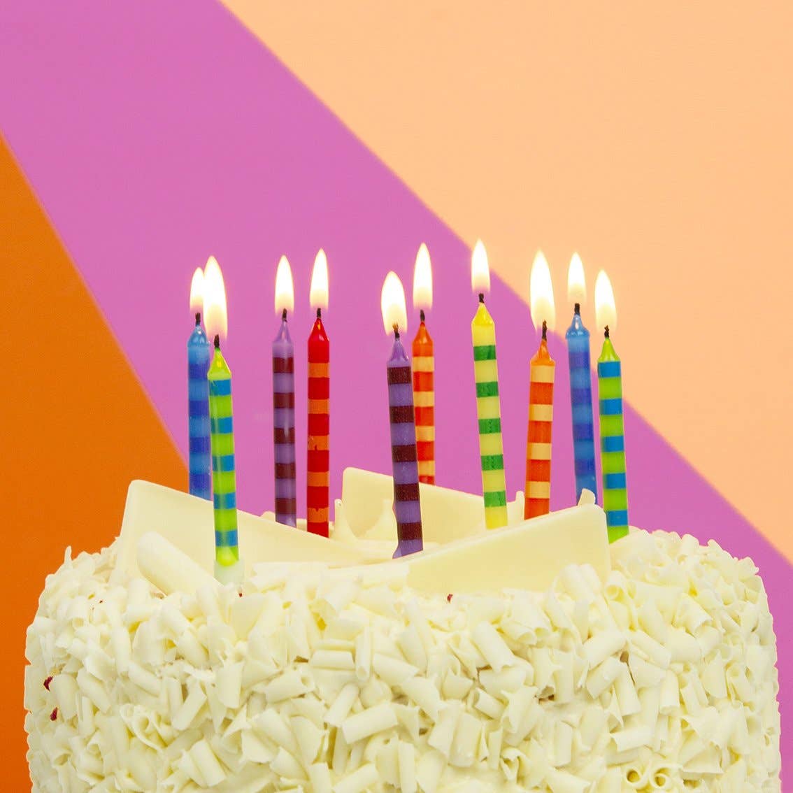 Birthday cake with colorful candles against a multicolored geometric background