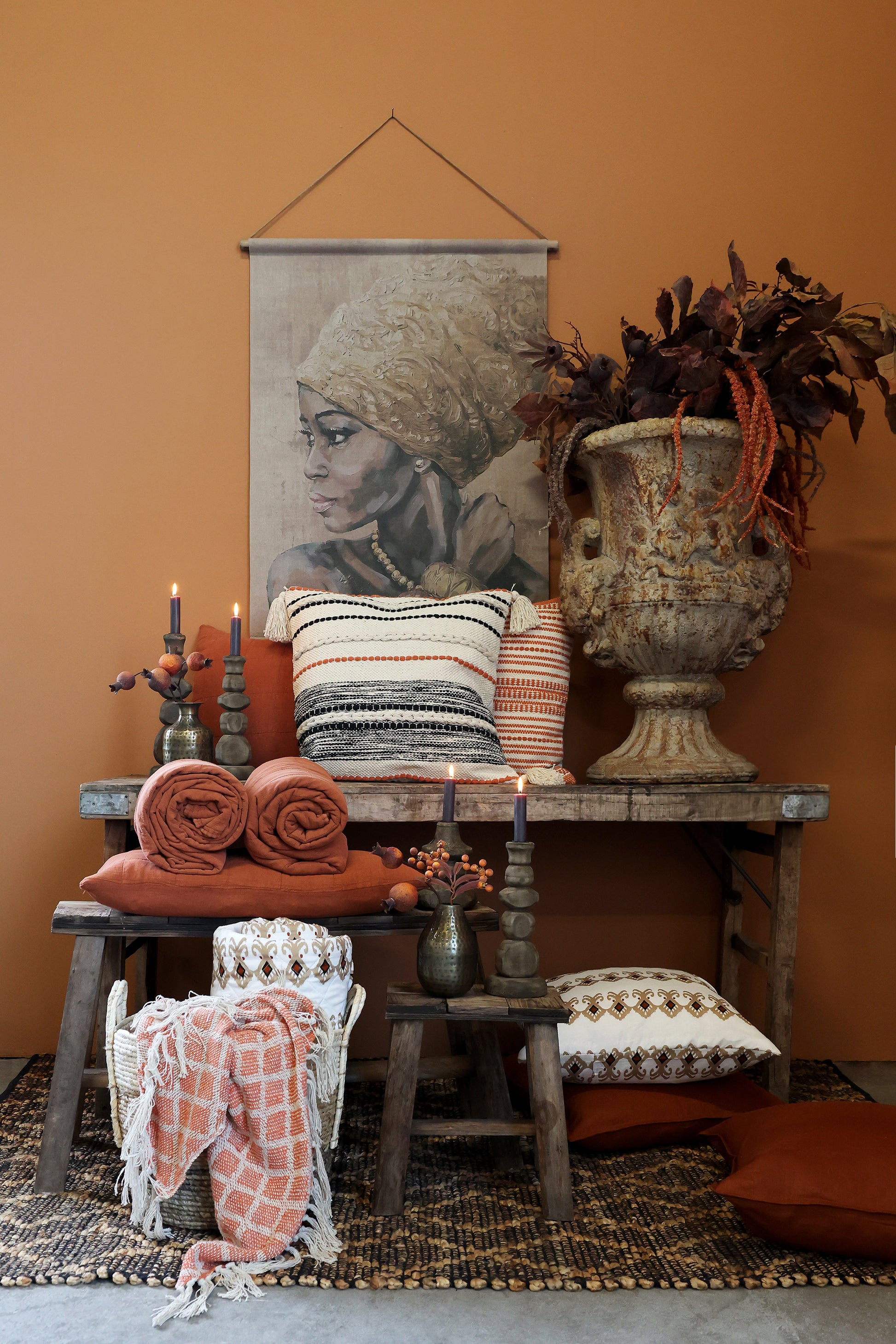 Cozy living room corner with a wooden table, pillows, and decorative items against an orange wall.