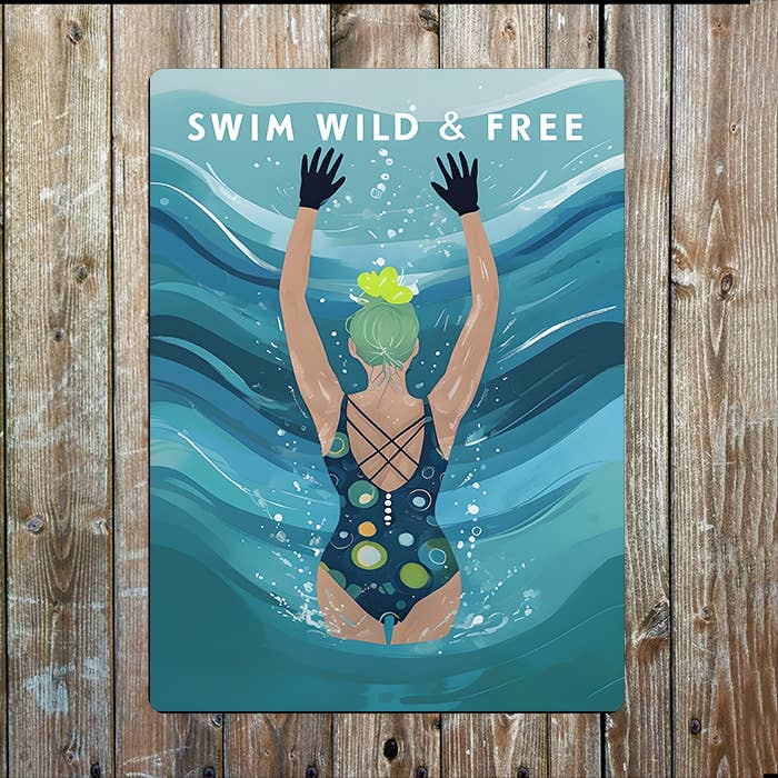 Poster with a swimmer underwater and 'Swim Wild & Free' text on a wooden background