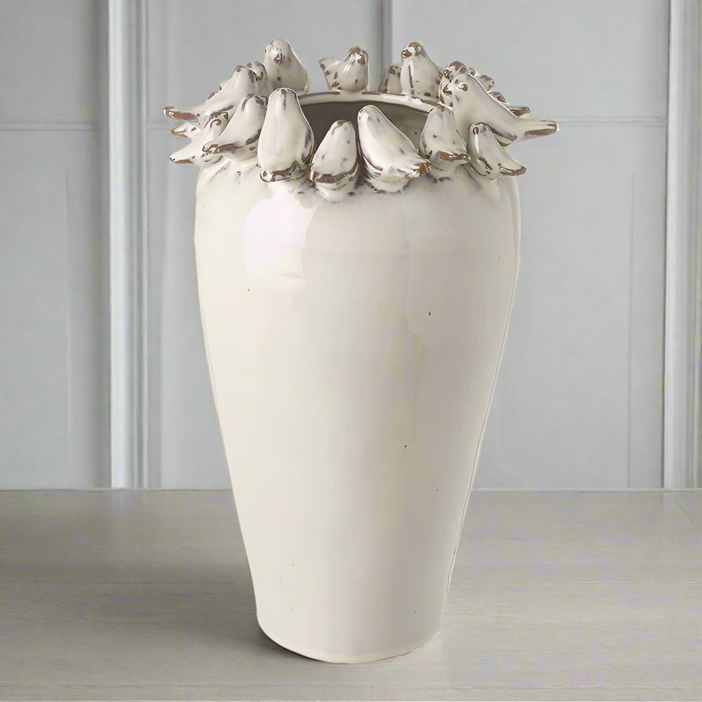 White ceramic vase with 3d bird design on a shelf background