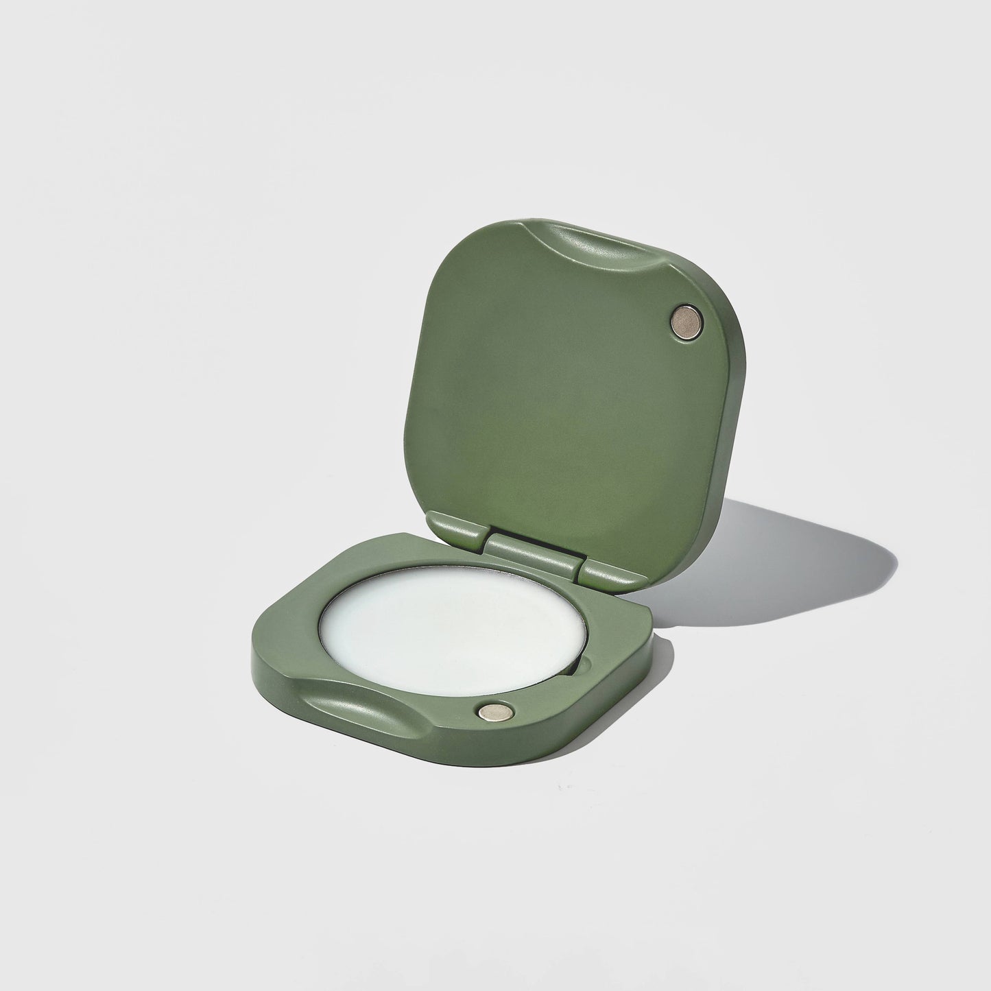 Green solid perfume balm holder on a light gray background