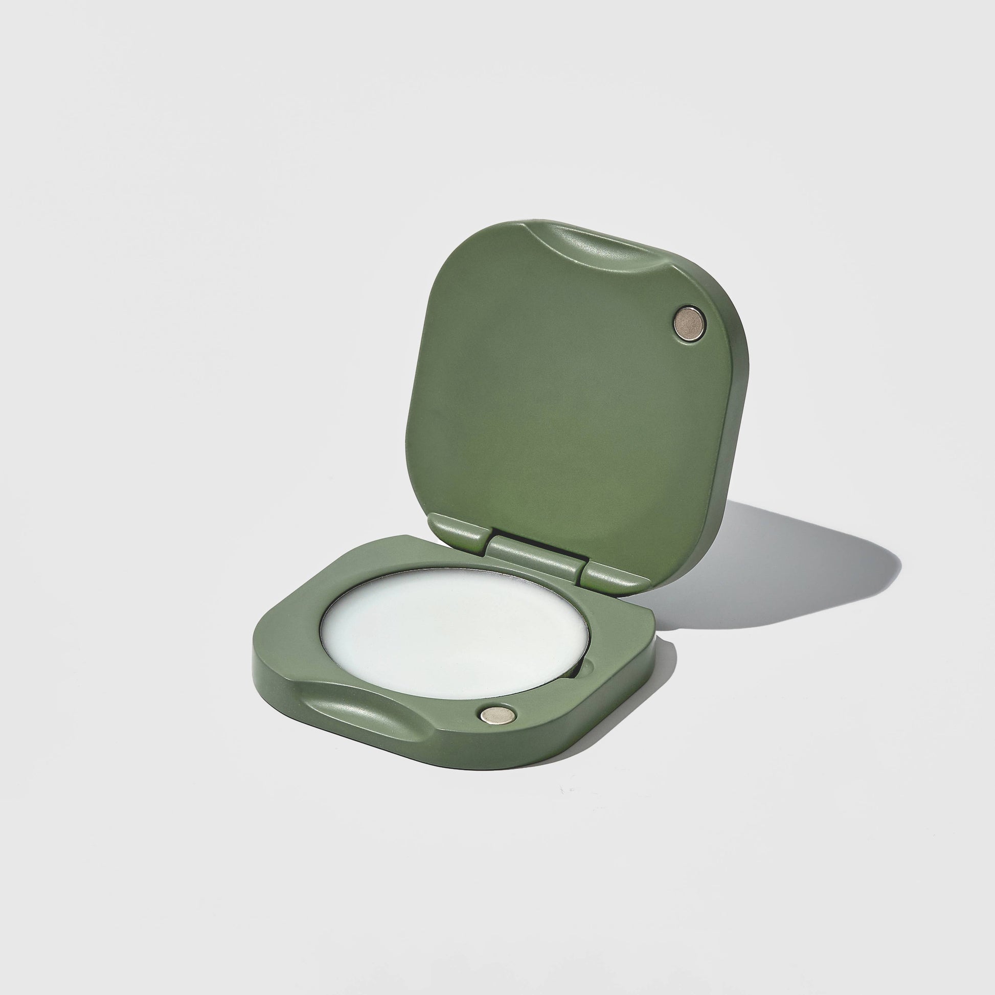 Green solid perfume balm holder on a light gray background