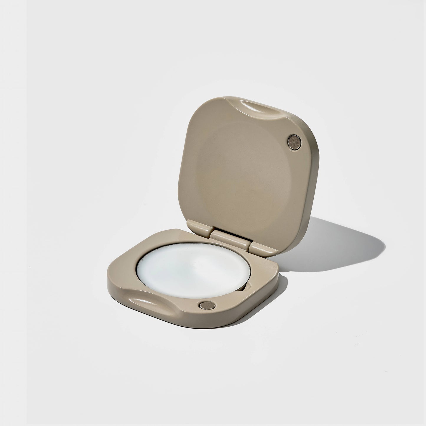 Beige coloured metal solid balm perfume container on a light gray background