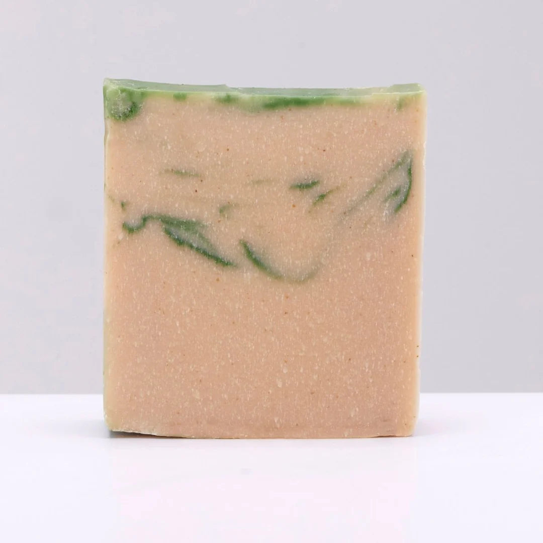 Bar of soap with green specks on a white background