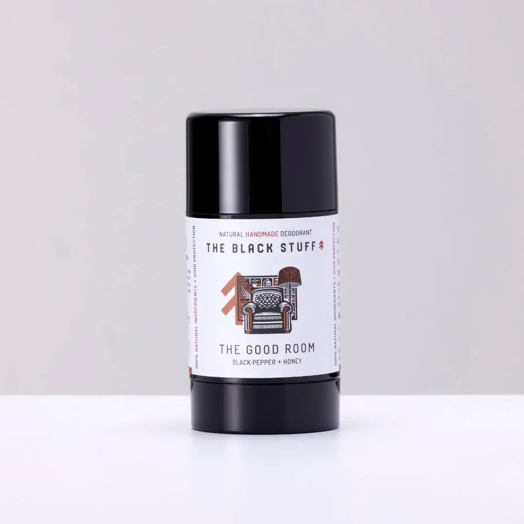 A stick deodorant labeled 'The Good Room' by The Black Stuff, with a black cap and a label that has text and an illustration of a chair.