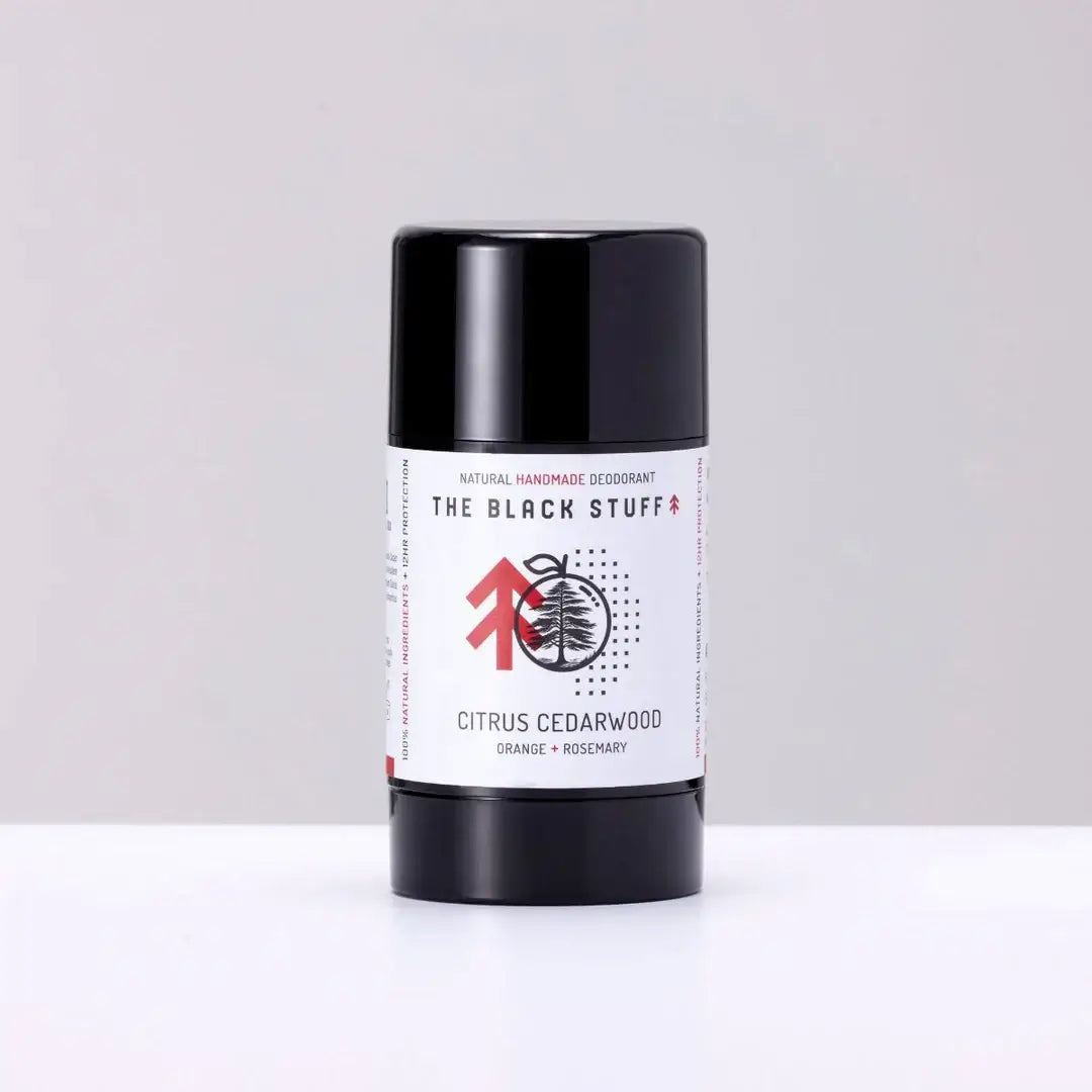 A stick deodorant with a black and white label reading 'The Black Stuff', 'Natural Deodorant', 'Citrus Cedarwood', and some other text. The deodorant is in a black cylindrical container.