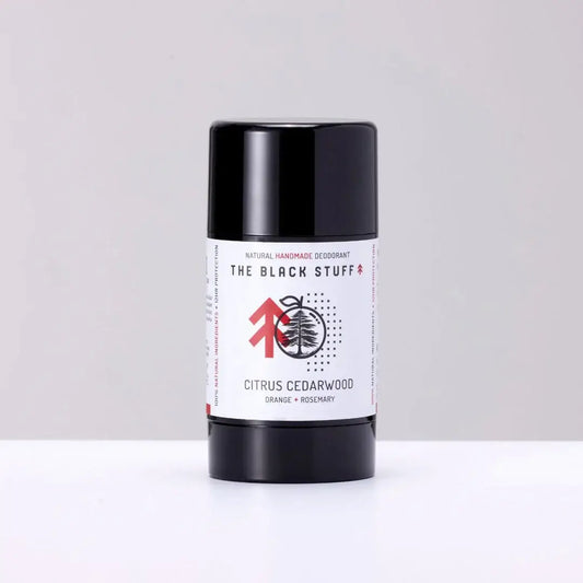 A stick deodorant with a black and white label reading 'The Black Stuff', 'Natural Deodorant', 'Citrus Cedarwood', and some other text. The deodorant is in a black cylindrical container.