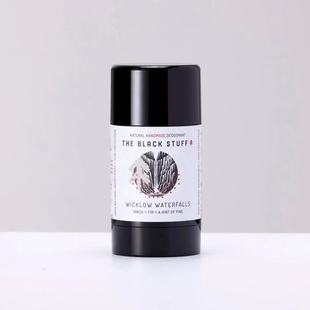 A stick deodorant with a label showing 'The Black Stuff' and 'Natural Deodorant - Wicklow Waterfalls'. The deodorant is in a black cylindrical container with a white label.