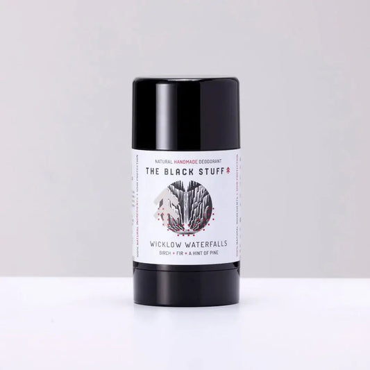 A stick deodorant with a label showing 'The Black Stuff' and 'Natural Deodorant - Wicklow Waterfalls'. The deodorant is in a black cylindrical container with a white label.