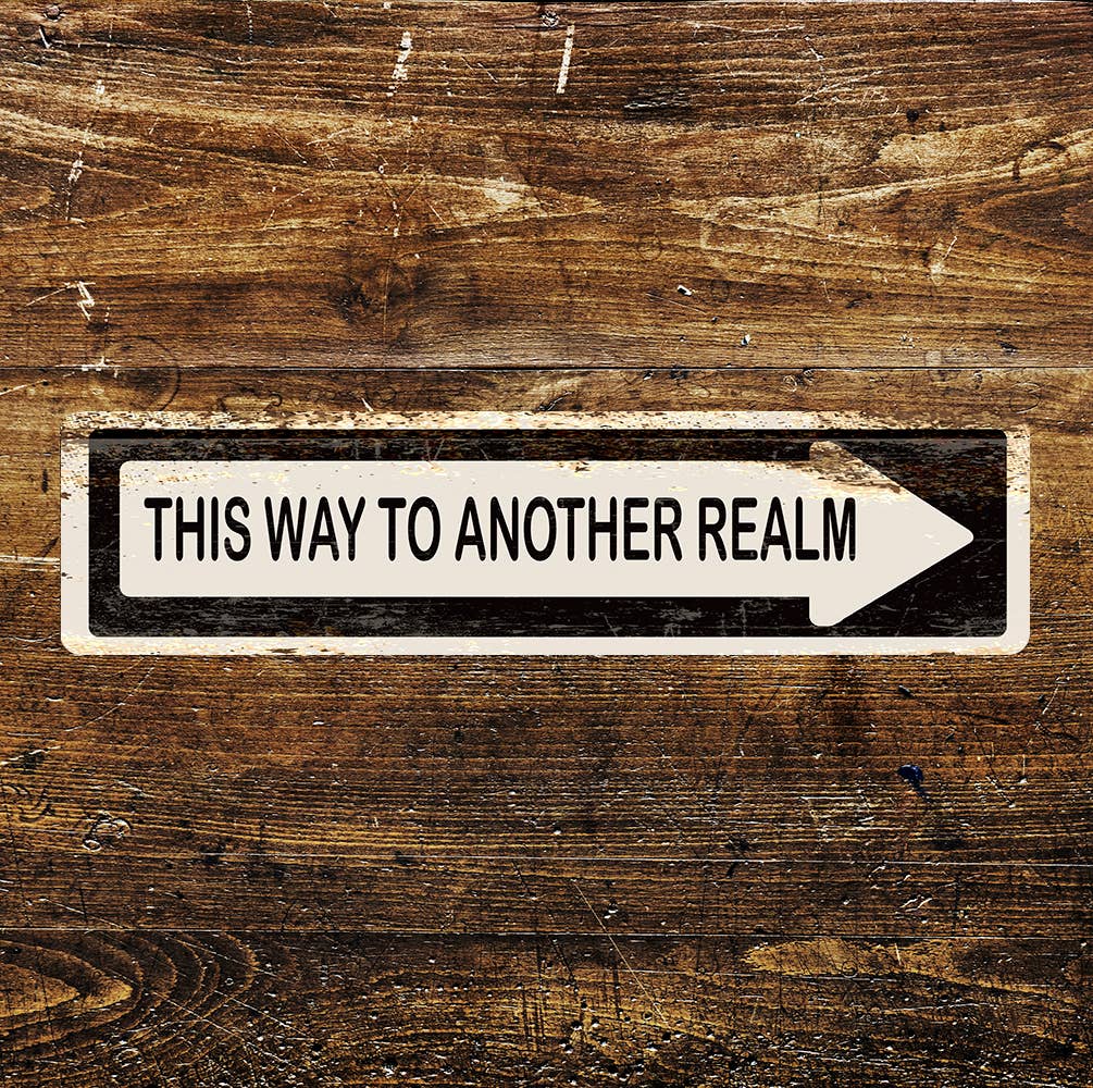 Wooden surface with a sign reading 'This way to another realm' on a white arrow.