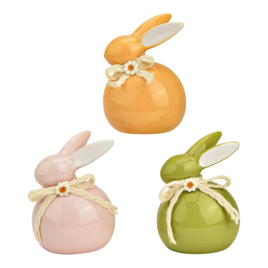 Three ceramic rabbits in orange, pink, and green on a white background.