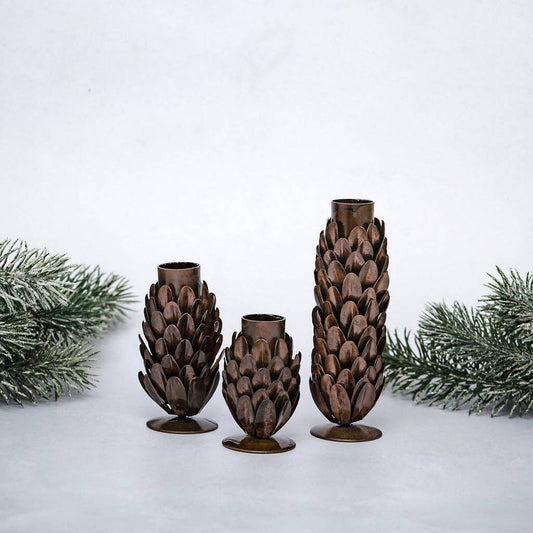 Three different sized pine cone candle holders on festive background