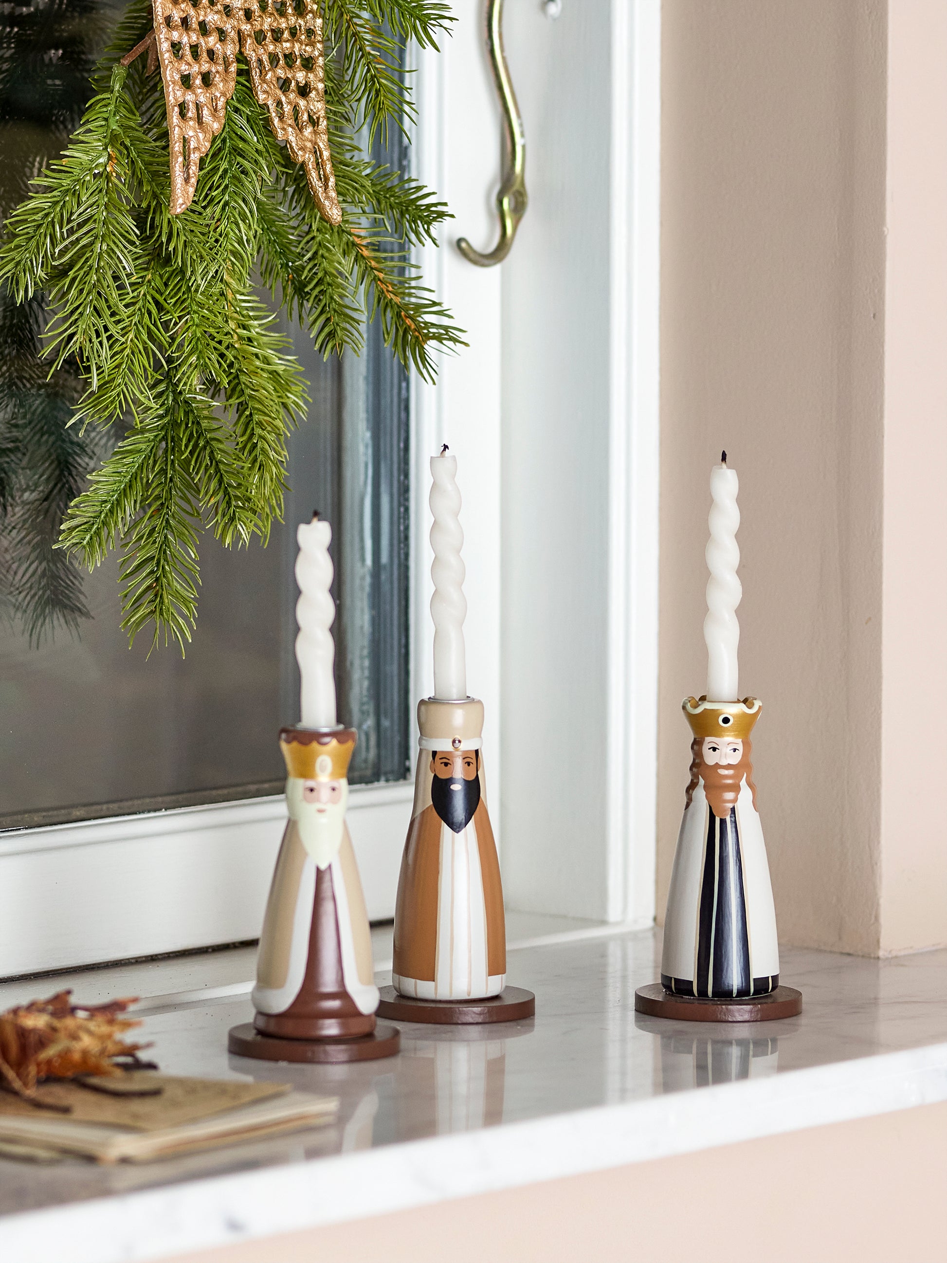 Three wise men painted candle holders with taper candles. Sitting on a windowsill