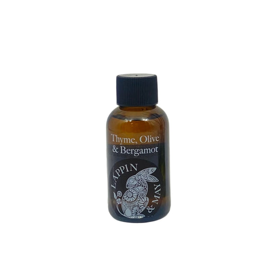 A small dark brown bottle with a black cap labeled 'Thyme, Olive & Bergamot' refills, indicating it is a fragrance or scent refill for a product.